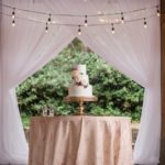 Cake under chandelier at garden wedding reception photographed by Meredith Ryncarz