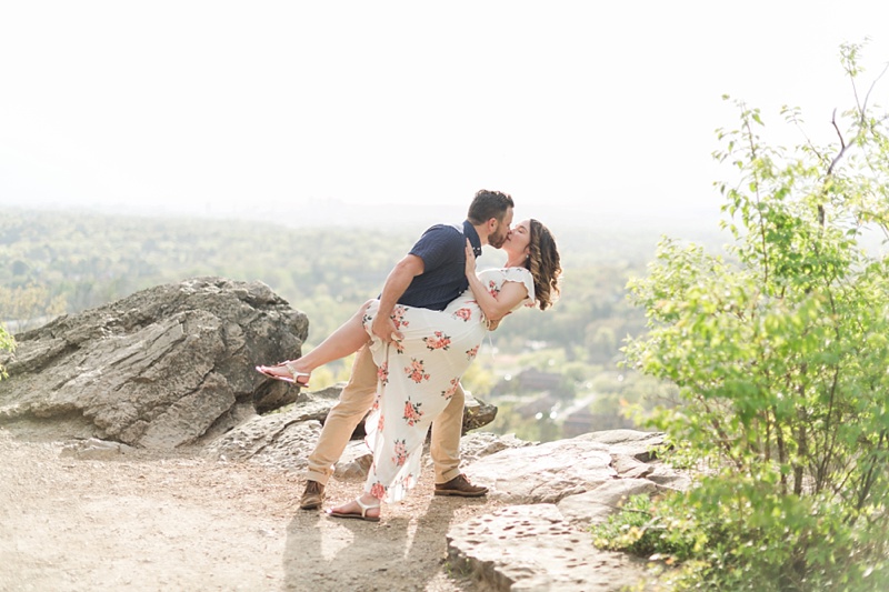 Groom dipping bride and kissing her on a cliff for an engagement session