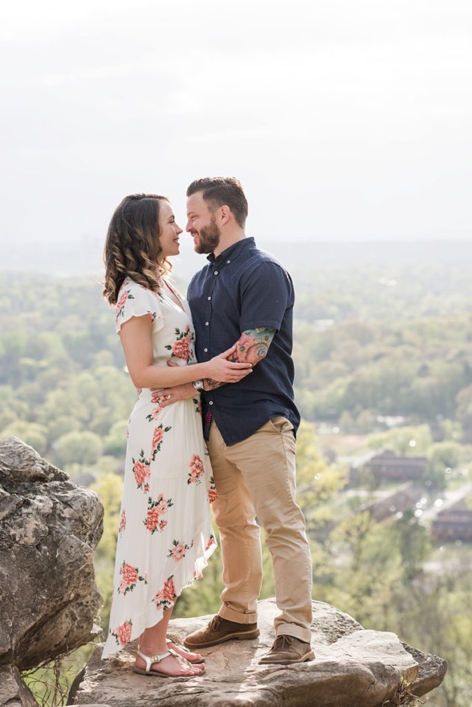 Engaged couple standing on cliff overlooking the city for an engagement session. 